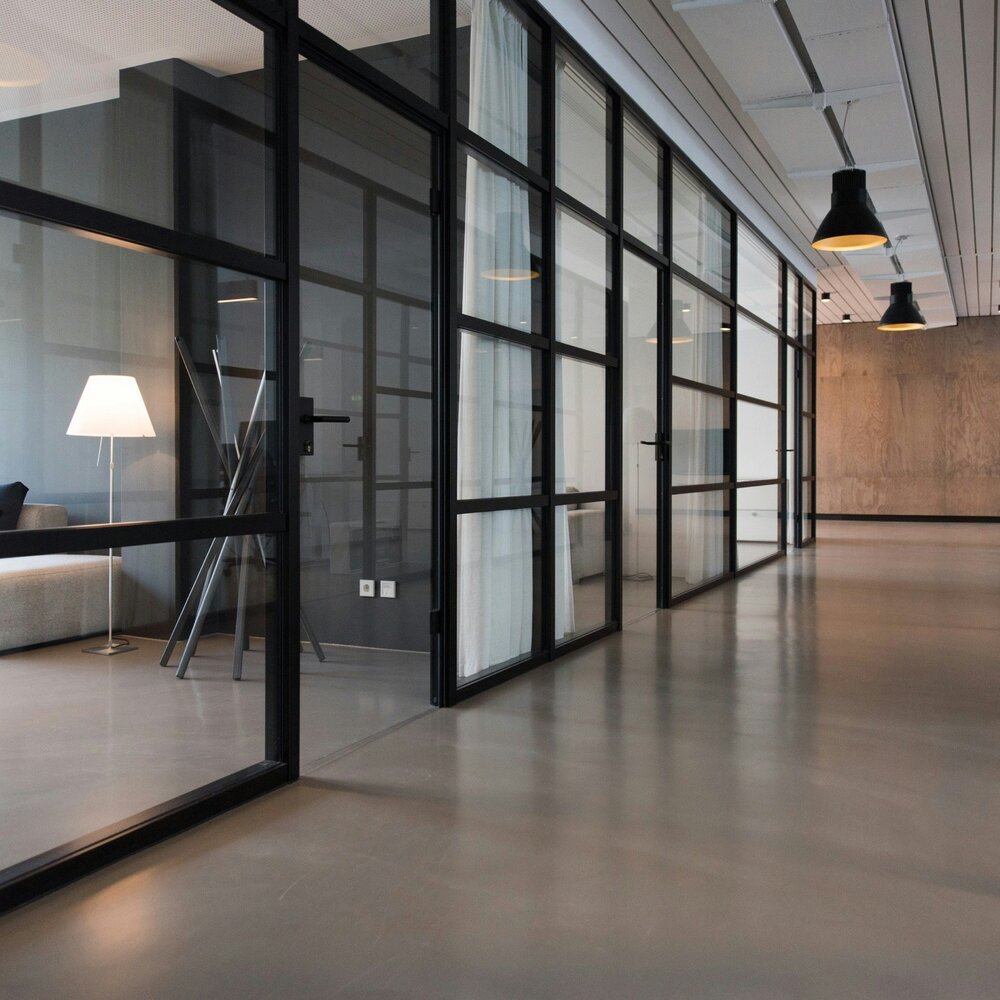 Moderner Büroflur mit Glaswänden und Stehleuchte
